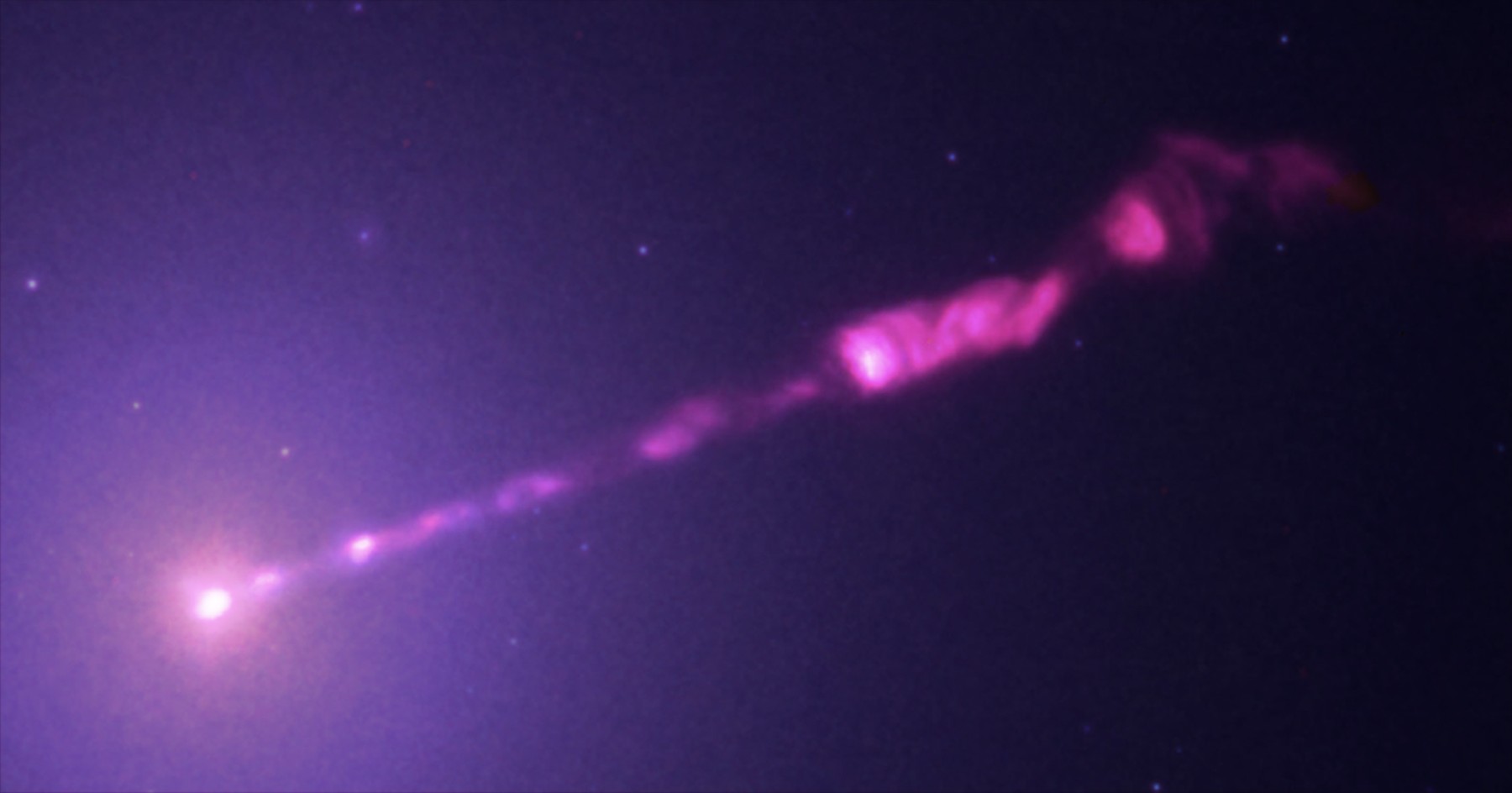 Composite observatory image of the M87 jet in X-ray, optical, infrared and radio, a knotted stream leaving the galactic core.