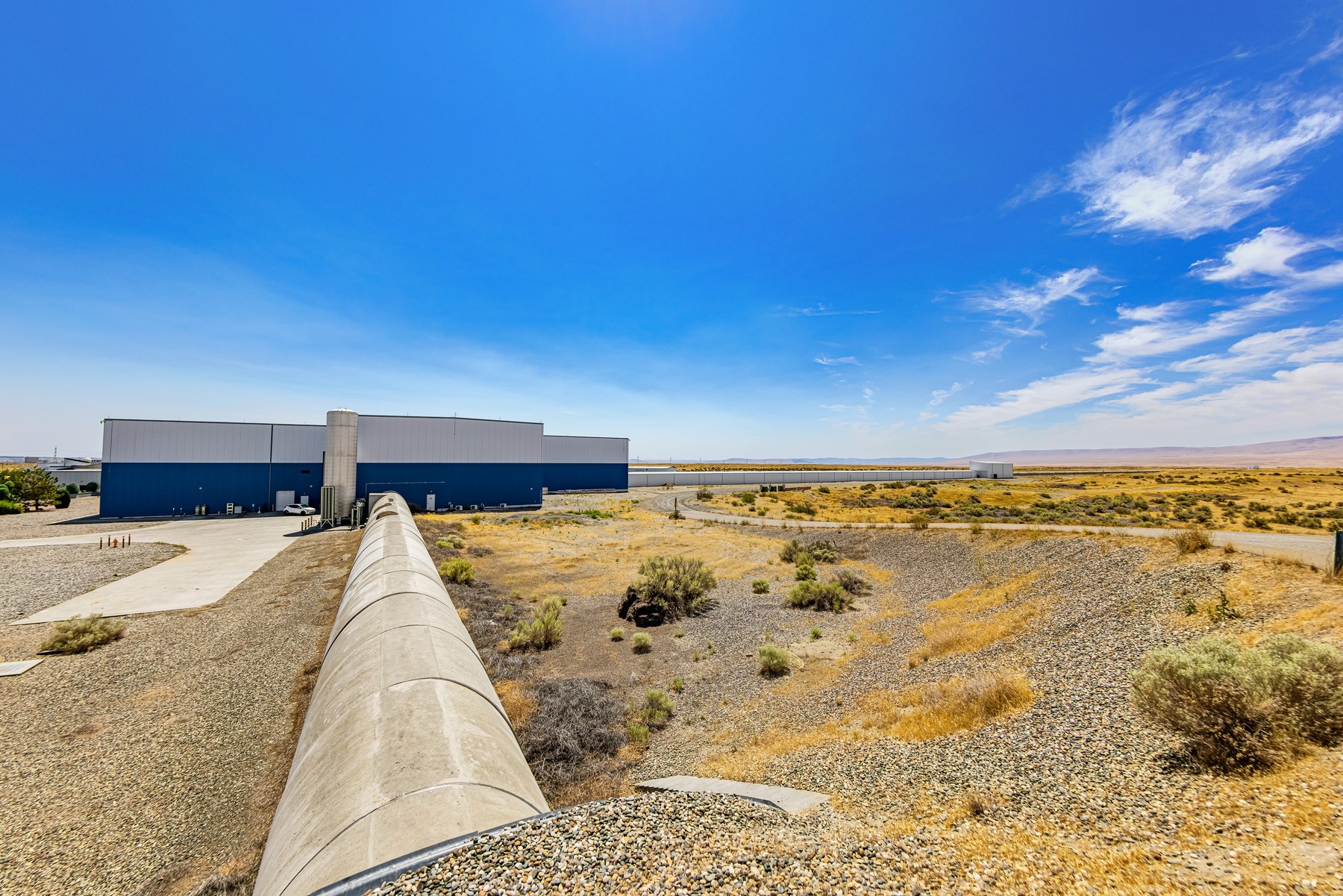 Aerial photograph of LIGO Hanford Observatory: two long perpendicular vacuum arms meeting at a corner station in the Washington desert.